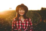 A smiling woman in a hat and flannel shirt smiles after finding neurodivergent support at NeuroSpark Health.