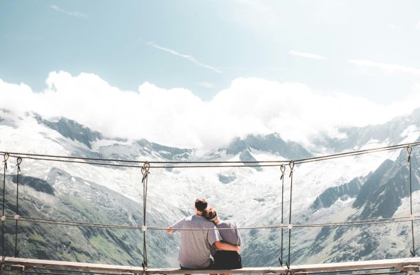 Two people sitting together on a bridge overlooking mountains, representing life and relationship coaching for autistic adults at NeuroSpark Health.