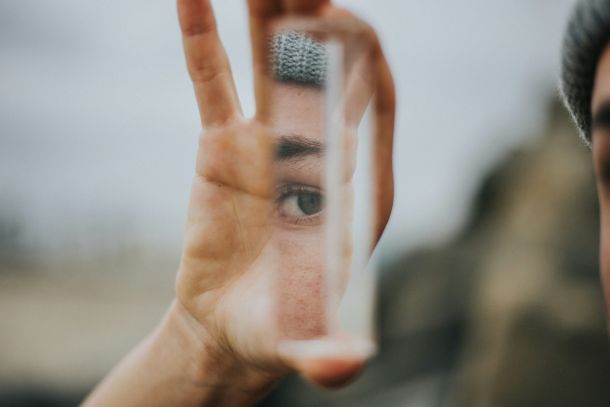 A person holding a mirror reflecting their eye, representing neurodivergent coaching.