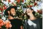 A couple stands under flowers smiling at each other celebrating an adult autism diagnosis.
